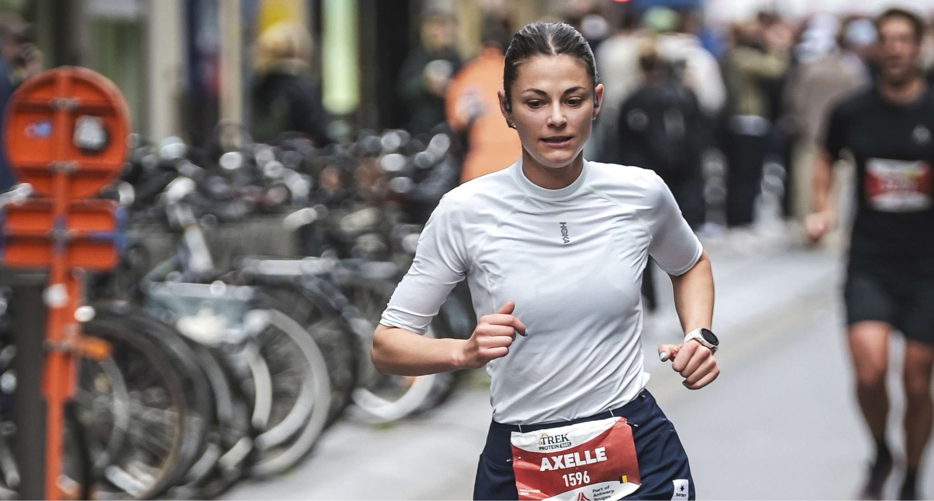La coureuse Axelle avance concentrée dans une rue urbaine pendant une course.
