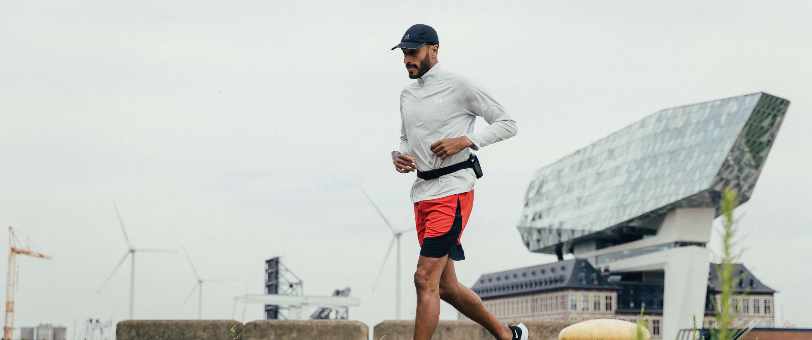 Coureur s’entraînant seul le long de l’eau dans un environnement urbain avec des bâtiments modernes en arrière-plan
