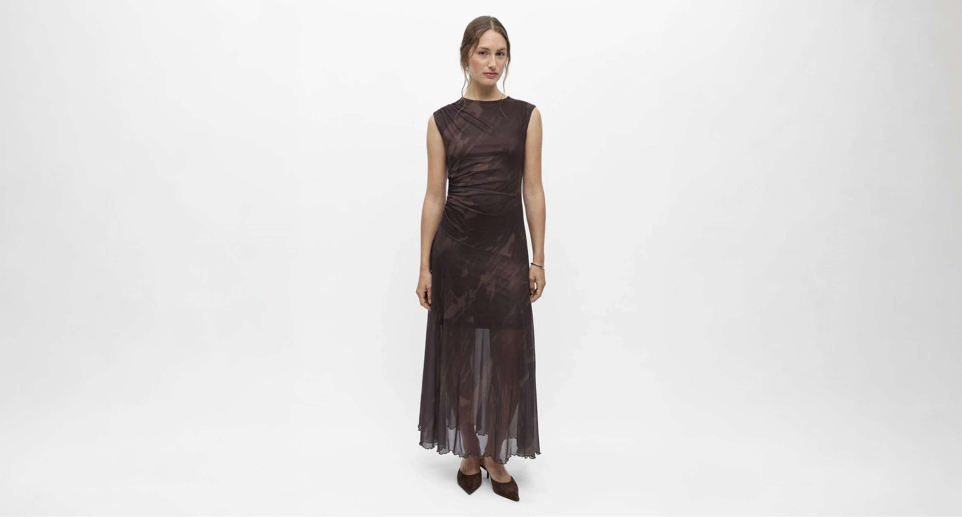 Robe longue brun foncé à silhouette ajustée et tissu transparent à partir des genoux.