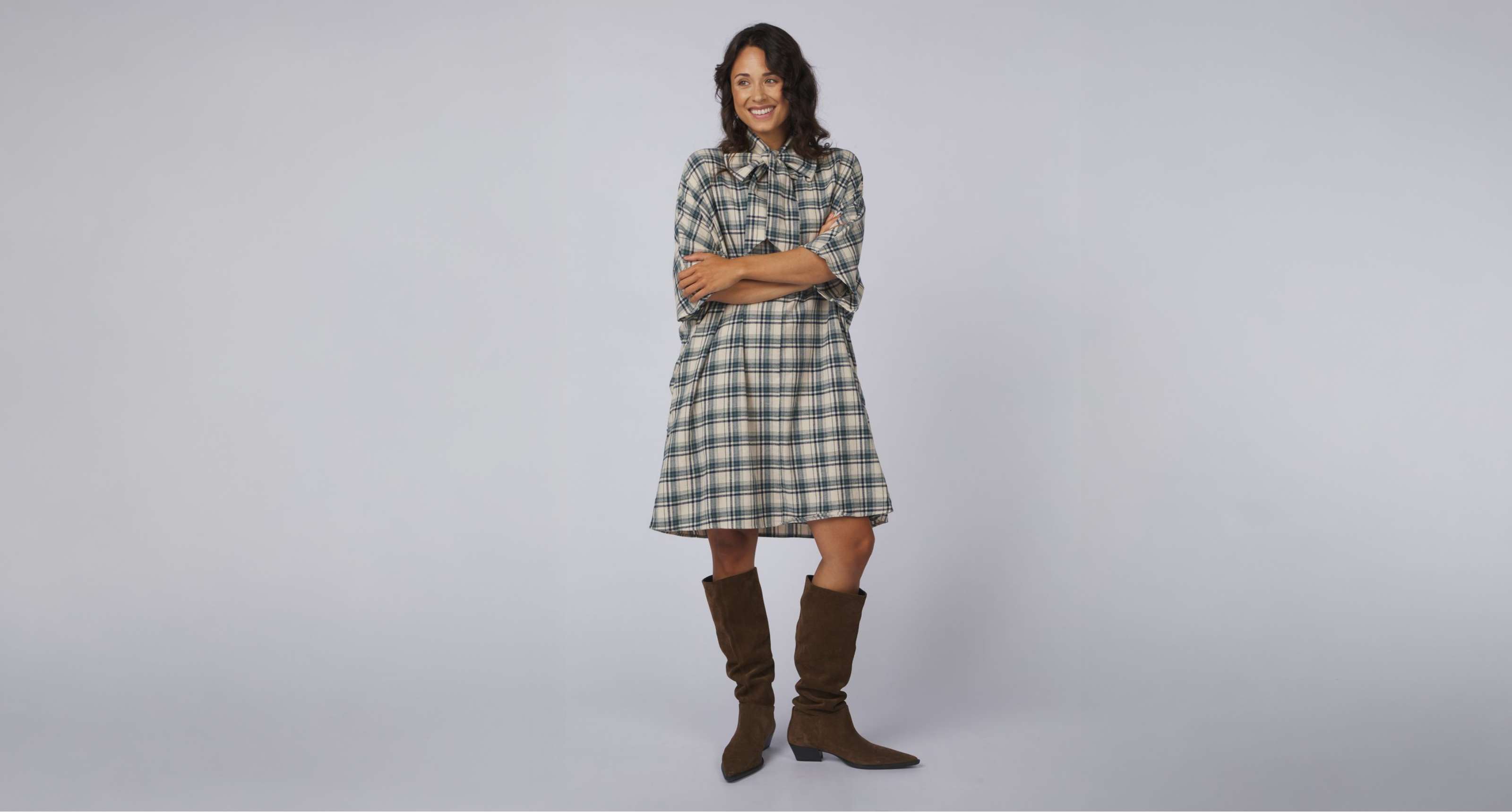 Une personne porte une robe chemise bordeaux rayée avec col, manches courtes et bottes brunes.