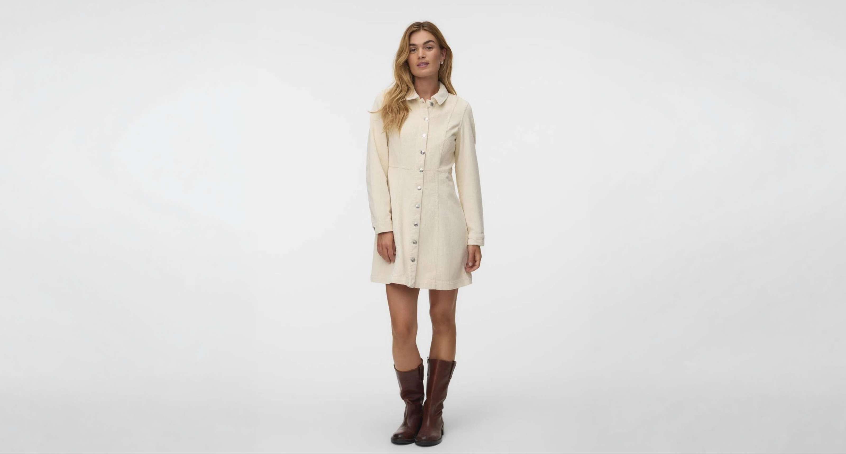 Une personne porte une mini-robe crème à manches longues, col et boutons sur le devant.