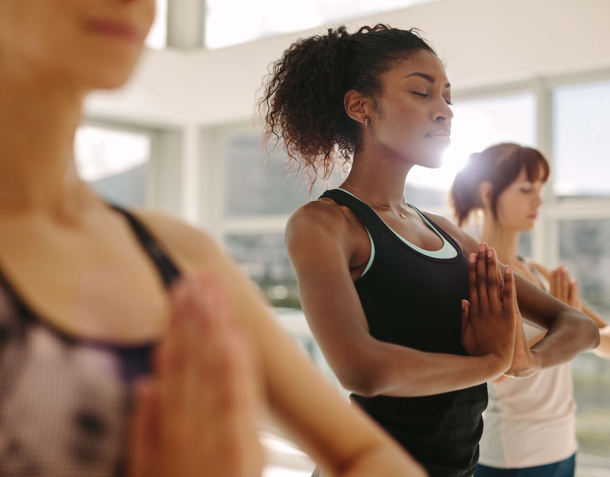 Groupe de personnes, yeux fermés, en posture de respiration avec les mains jointes.