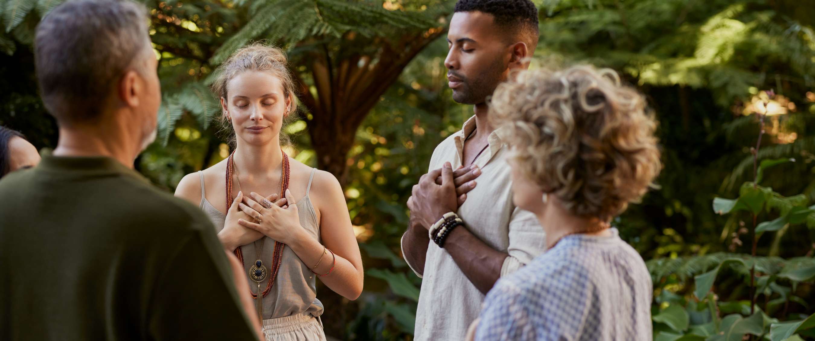 Groupe de personnes méditant yeux fermés dans un environnement naturel.
