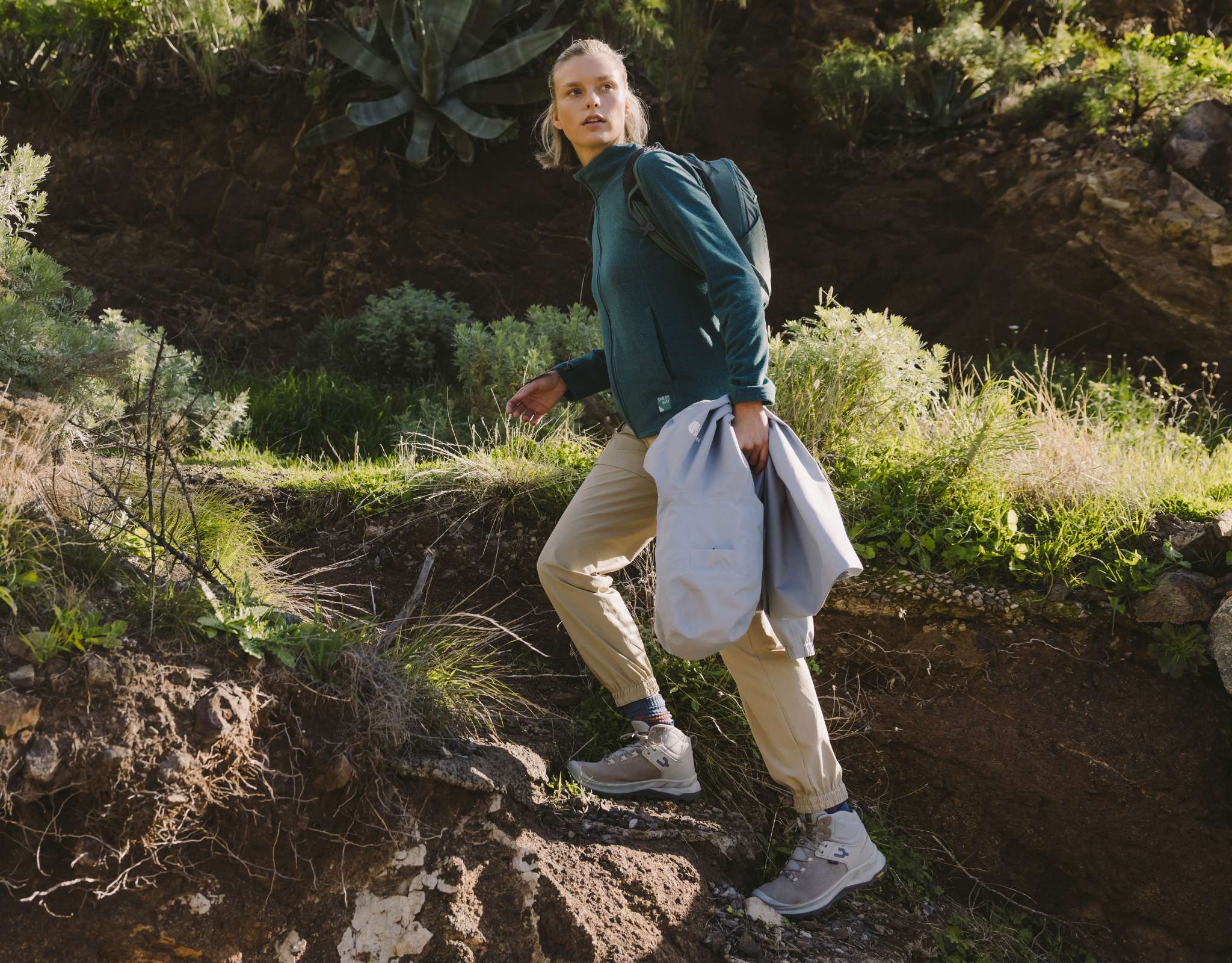 Personne en chaussures de randonnée sur un chemin non pavé entouré de végétation.