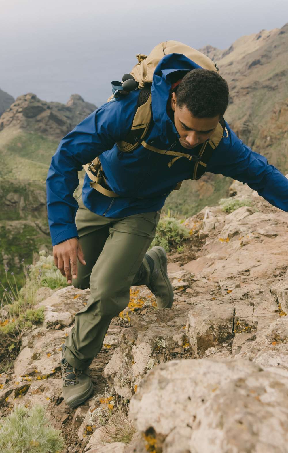 Homme grimpant sur des rochers avec un sac à dos dans un paysage de montagne