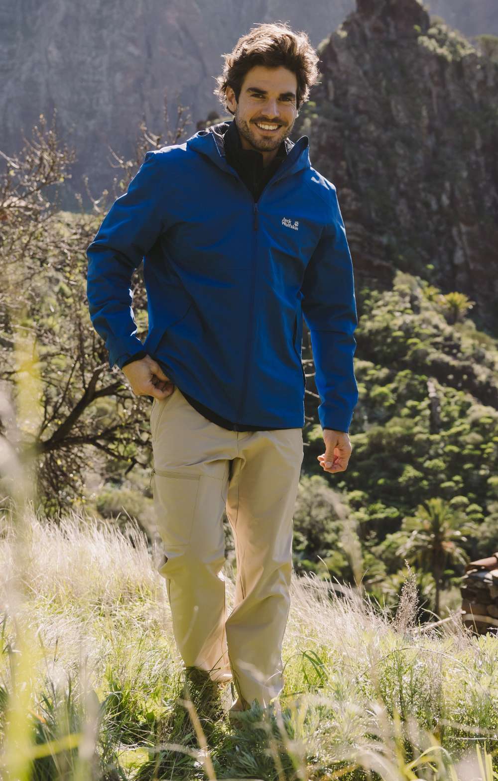 Randonneur en pantalon beige marchant dans un paysage de montagne